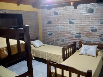 a room with two beds and a brick wall at Cabañas Buen Dia in Villa Serranita