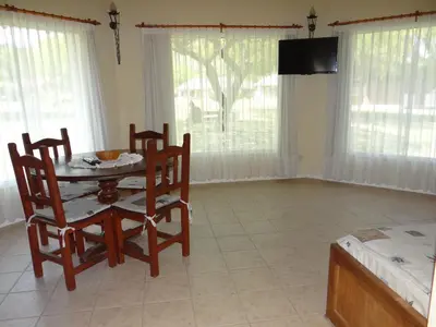 a dining room with a table and chairs and a television at Solar Encantado Cabañas & Chalet in Villa General Belgrano