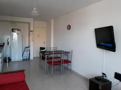 a living room with a table and chairs and a television at Departamento Luxor in Villa Carlos Paz