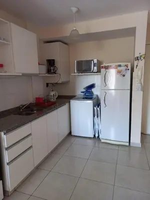 a kitchen with white cabinets and a white refrigerator at Departamento Luxor in Villa Carlos Paz