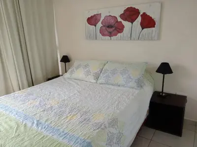 a bedroom with a bed with red flowers on the wall at Departamento Luxor in Villa Carlos Paz