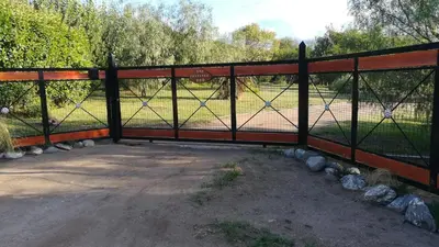 a fence with a gate with a field behind it at Cabañas Valentina in Cortaderas