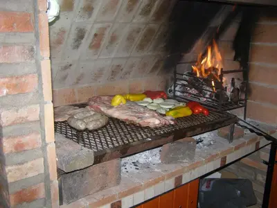 a grill with meat and vegetables in a brick oven at Cabañas Valentina in Cortaderas