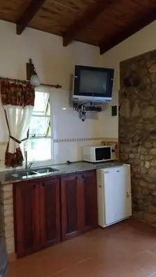 a kitchen with a refrigerator and a tv on the wall at Entre Flores in Los Hornillos