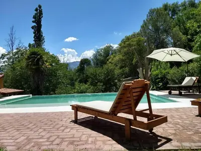 a wooden chair with an umbrella next to a pool at Entre Flores in Los Hornillos