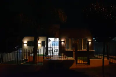 a house lit up at night with a fence at La Colina in Villa Carlos Paz