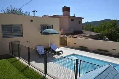 a house with a pool and two chairs and an umbrella at La Colina in Villa Carlos Paz