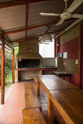 a dining room with a wooden table and a kitchen at Feliza Hostel in Villa Carlos Paz