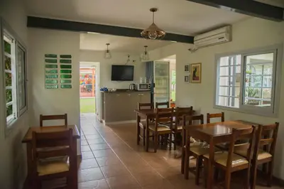 a dining room with tables and chairs and a kitchen at Feliza Hostel in Villa Carlos Paz