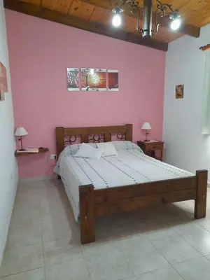 a bedroom with a large bed in a pink wall at Cabañas Brisas Del Mirador in Bialet Massé