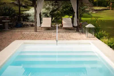 a swimming pool in a yard with two chairs at La Hondonada in San Javier