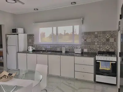 a kitchen with white appliances and a glass table at Sierras Encantadas Cabañas in Panaholma