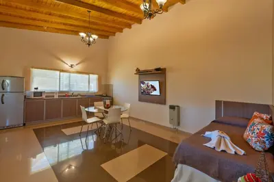 a kitchen and living room with a bed and a table at Sierras Encantadas Cabañas in Panaholma