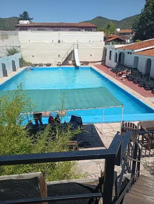 a large blue swimming pool with a table and chairs at Palmas del Lago in Villa Carlos Paz