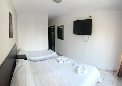 a bedroom with two beds and a flat screen tv at Palmas del Lago in Villa Carlos Paz