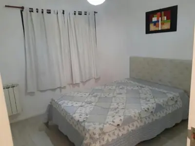 a bedroom with a bed with white walls and curtains at Edificio Hipolito Irigoyen in Villa Carlos Paz