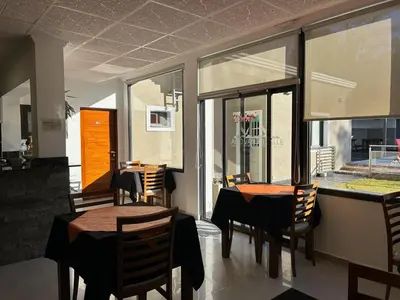 a dining room with tables and chairs and windows at Alto Valle in Nono