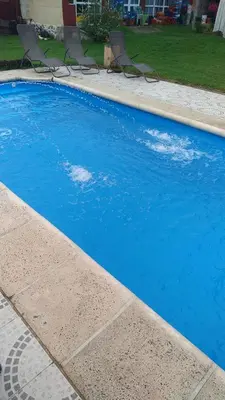 a blue swimming pool with chairs in a yard at Cabañas El Paraiso in Villa Parque Siquiman