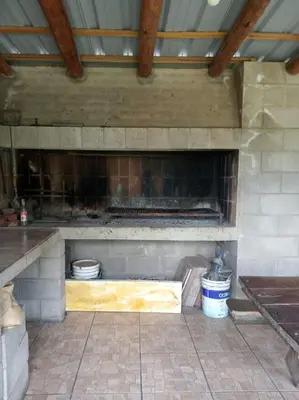 a kitchen with a stone fireplace in a building at Cabañas El Paraiso in Villa Parque Siquiman