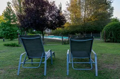 two chairs sitting in the grass near a pool at Finca El Amparo in Los Reartes