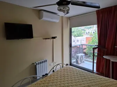 a bedroom with a bed and a window with a television at Departamento Eutico in Villa Carlos Paz