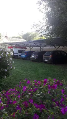a group of cars parked in a parking lot with purple flowers at El Cortijo de la villa in Villa Independencia