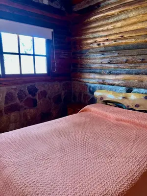 a bedroom with a bed in a log cabin at Cabañas y Toboganes Rancho la Ñata in Mina Clavero