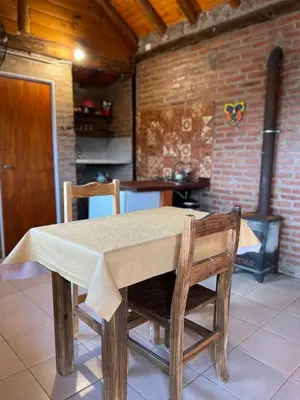 a wooden table with two chairs and a kitchen at Cabañas y Toboganes Rancho la Ñata in Mina Clavero