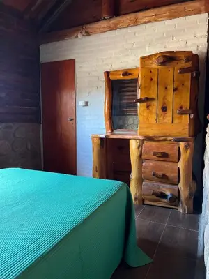 a bedroom with a bed and a dresser in a room at Cabañas y Toboganes Rancho la Ñata in Mina Clavero