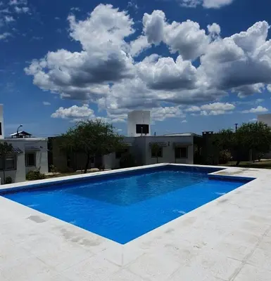 a large blue swimming pool in front of a building at La Catalina Traslasierra in Nono