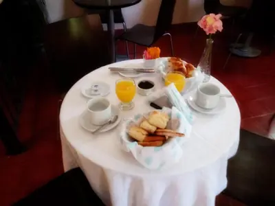 a white table with a plate of food and glasses of orange juice at Hotel Sierras in Mina Clavero