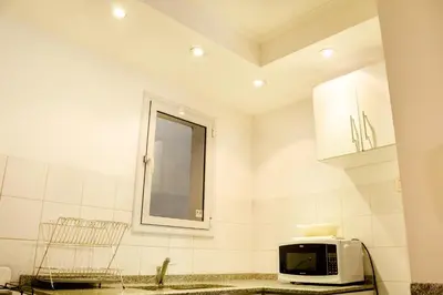 a white kitchen with a microwave and a mirror at Lofty Departamentos Temporarios in Cordoba