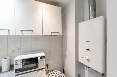 a microwave in a kitchen with white tiles at Lofty Departamentos Temporarios in Cordoba