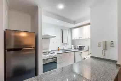 a kitchen with white cabinets and a stainless steel refrigerator at Lofty Departamentos Temporarios in Cordoba