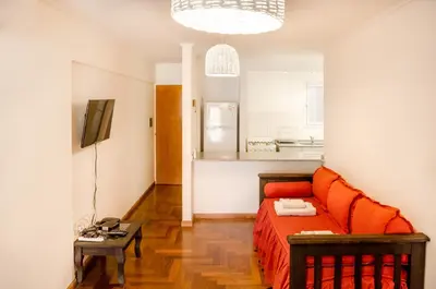 a living room with an orange bed and a table at Lofty Departamentos Temporarios in Cordoba