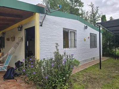 a white building with a window and some flowers at Cabaña Refugio De Caminantes in Tanti