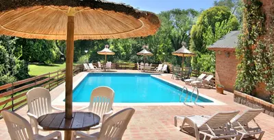 a pool with chairs and a table with an umbrella at Grenouille in Villa General Belgrano