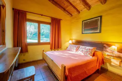 a bedroom with a bed with orange sheets and a window at Grenouille in Villa General Belgrano