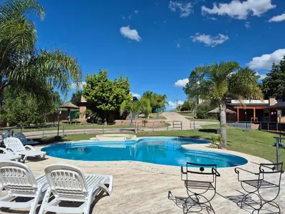 a swimming pool with white chairs and a table at Solares de Tanti in Tanti Nuevo