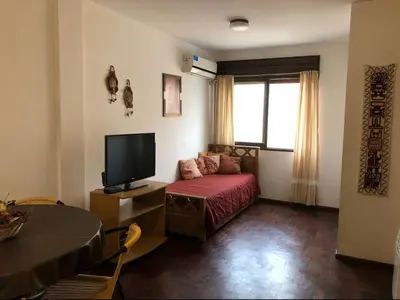 a living room with a bed and a television at Edificio Trebol - Departamento en pleno centro de Carlos Paz in Villa Carlos Paz