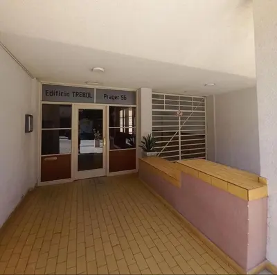 an entrance to an office building with a wooden bench at Edificio Trebol - Departamento en pleno centro de Carlos Paz in Villa Carlos Paz