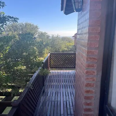 a balcony with a wooden floor and a brick wall at Complejo los Espinillos de Merlo in Merlo