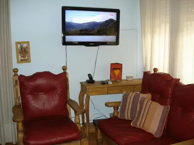 a living room with two chairs and a television on the wall at Casa Villa Carlos Paz in Villa Carlos Paz