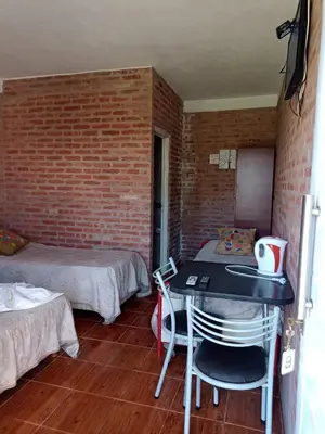 a room with two beds and a table and chairs at Complejo Navi in Mina Clavero
