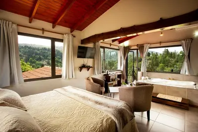a bedroom with a bed and a desk and a tub at SUITES ALITHUÉ in La Cumbrecita