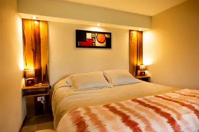 a bedroom with a bed with two windows and two lamps at SUITES ALITHUÉ in La Cumbrecita
