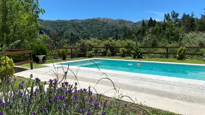 a swimming pool in a garden with purple flowers at SUITES ALITHUÉ in La Cumbrecita