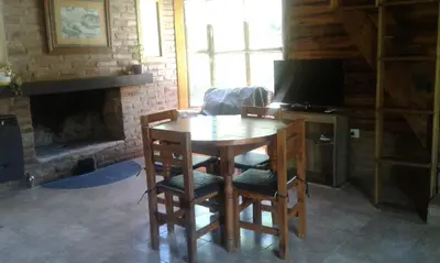 a dining room with a table and chairs and a television at Cabaña Atha Iti in Villa General Belgrano