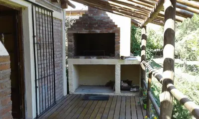 a porch with a fireplace on a house at Cabaña Atha Iti in Villa General Belgrano