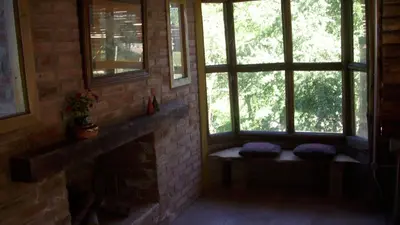 a room with windows and a bench in front of a fireplace at Cabaña Atha Iti in Villa General Belgrano
